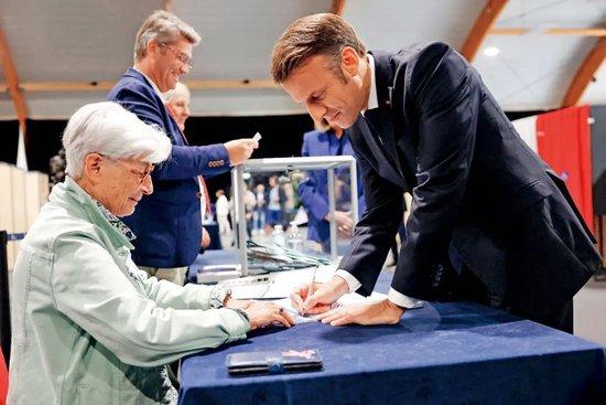 7月7日，法国勒图凯，法国总统马克龙（右）抵达投票站，参加法国国民议会选举第二轮投票。图/视觉中国 