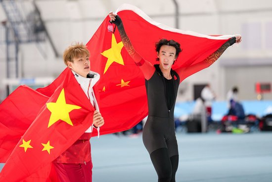在亚冬会速度滑冰男子5000米决赛中获得金牌的吴宇和获得银牌的刘瀚彬身披国旗绕场