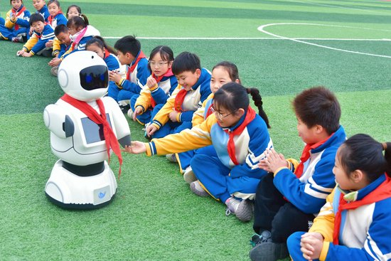 　△2025年3月10日，江苏南通，如皋经济技术开发区实验小学课间，学生与智能机器人“宾果”互动。