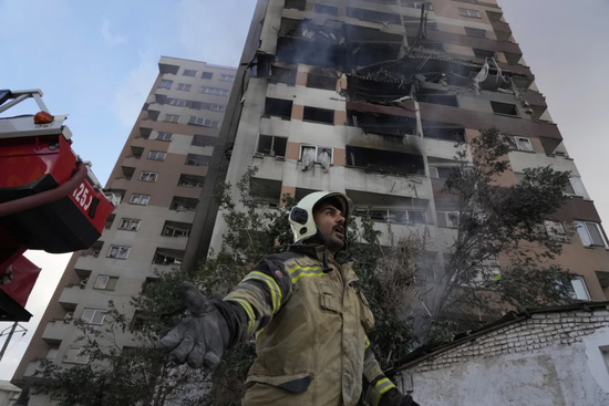 ·当地时间6月13日，伊朗消防员从德黑兰市一座被以军轰炸后的公寓楼前走过。
