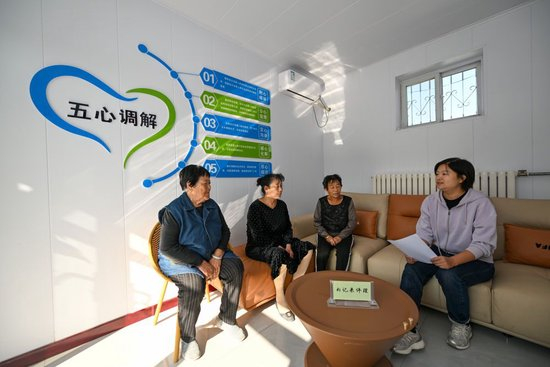 在天津市宁河区芦台街道金华路社区，社区党总支副书记吴蕊（右一）就社区监控设备安装问题为社区居民进行解答（2024年10月11日摄）。金华路社区积极践行新时代“枫桥经验”，将原社区居委会闲置用地提升改造成为联络群众的基层综合治理阵地——“解铃小院”。新华社记者 孙凡越 摄
