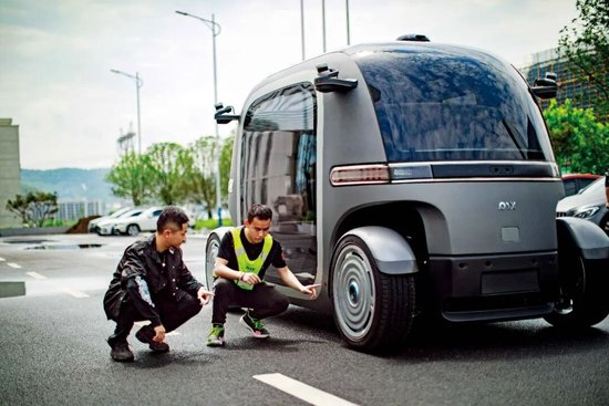 2023年6月14日，在贵阳市高新区生态科技产业园一家无人驾驶汽车企业内，就读于新加坡国立大学机器人专业的实习生李昂民荃（左）和同事张军文一起调试车辆。图/新华