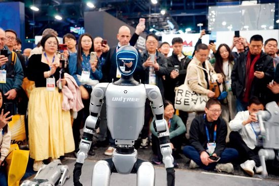  2025年 1月8日，在美国拉斯维加斯消费电子展上，人们在宇树科技展区观看机器人展示。图/新华