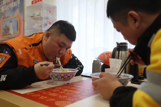2月10日，外卖员张瑞强（左）在新街口街道父母食堂就餐。新华社记者 卢烨 摄