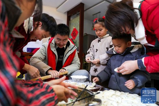 ↑ 2月16日，在江苏省扬州市邗江区荷叶小区一户人家，大人带着孩子包饺子。新华社发（齐立广 摄）