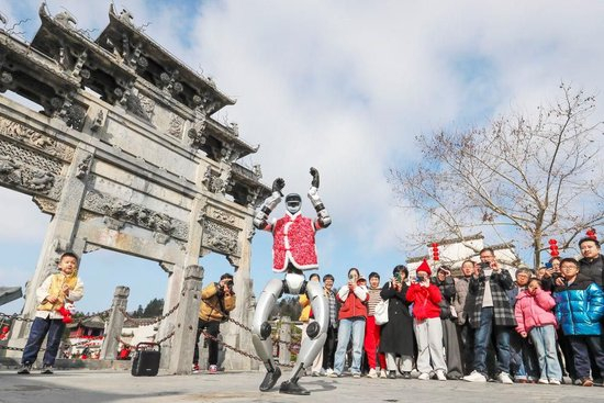 　△2026年2月18日，游客在安徽黟县西递古村观看机器人表演。