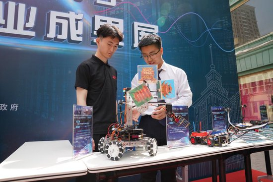  2024年5月13日，在哈尔滨工业大学学生创新创业成果展现场，参展团队成员展示一款智能车。新华社记者 王松 摄