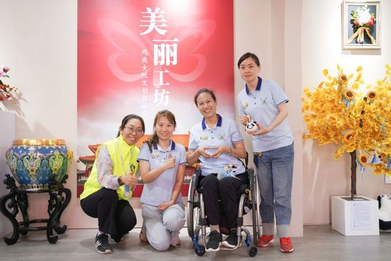 北京新生命养老助残服务中心主任唐占鑫（右二）团队在“美丽工坊”残疾女性文创作品展上。（受访者供图）