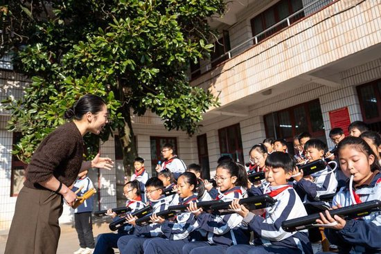 2026年1月13日，在湖南益阳南县三仙湖镇中心小学，音乐老师（左一）指导学生练习口风琴。新华社记者 陈思汗 摄