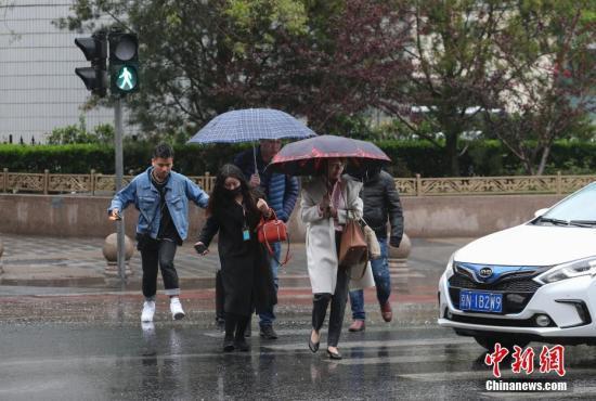  图为民众在雨中出行。 中新社记者 贾天勇 摄
