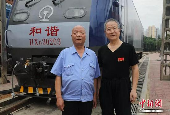  曹均宽（左）、李钰明在新型和谐大功率电力机车前合影。宝鸡机车检修厂供图