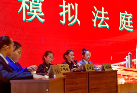 △2023年12月1日，新疆乌鲁木齐的学生们通过多种形式学习宪法知识。图为学生在模拟法庭中模仿“庭审”。