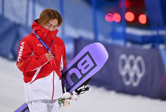  2月7日，季军中国选手苏翊鸣在单板滑雪男子大跳台颁奖仪式后查看奖牌。新华社记者 张宏祥 摄