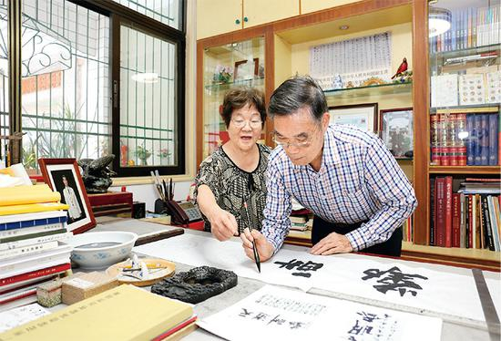 麦贤得受伤后，右手一度不能活动。在李玉枝的陪伴和护理下，他以顽强的毅力刻苦练习，不仅重新举起了右手，还练出了一手好字。图为李玉枝陪同丈夫麦贤得练习书法。 李玉枝供图