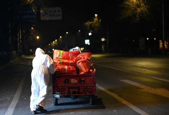  12月22日晚，陕西省石油化工学校工作人员在隔离栏处转运大米。新华社记者 李一博 摄