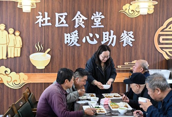 在江苏省扬州市江都区邵伯镇甘棠社区幸福邻里食堂，社区工作人员（左三）给老年居民端汤（2026年4月29日摄）。新华社记者 季春鹏 摄