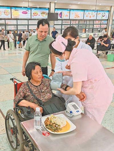 7月6日，在湖南省岳阳市华容县职业中专安置点，医护人员为转移群众测量血压。喻熙荣摄（人民视觉）