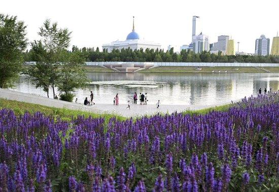 6月13日,人们在哈萨克斯坦首都阿斯塔纳的伊希姆河畔休闲。 新华社记者 燕雁 摄