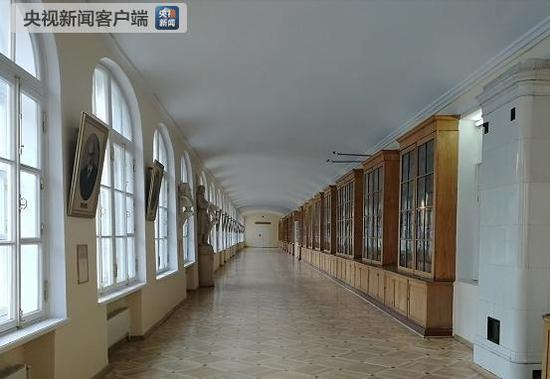 △在2层大讲堂外的走廊上，一侧橱窗里摆满古籍，另一侧挂着人物画像。（央广记者刘会民拍摄）