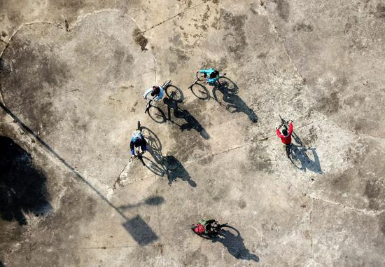 俊俊（左一）和小伙伴们骑单车在小区公园内追逐玩耍（2017年11月26日摄）。