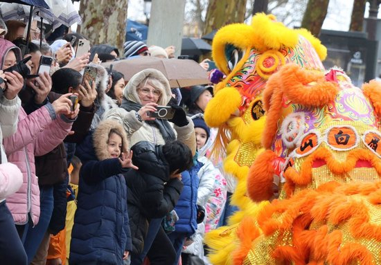 2026年2月1日，在法国首都巴黎的香榭丽舍大街，人们观看“欢乐春节满巴黎·龙狮贺岁舞香街”春节巡游活动中的醒狮表演。新华社记者 张百慧 摄
