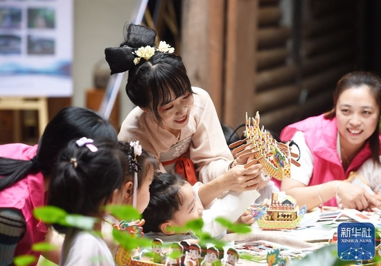 6月2日，在浙江省杭州市临安区玲珑街道崂山村，玲珑街道中心幼儿园的小朋友在志愿者协助下制作龙舟。新华社发（金凯华摄）