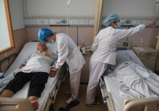  △6月14日，两名医护人员在为两名伤者输液。中新社记者 王刚 摄