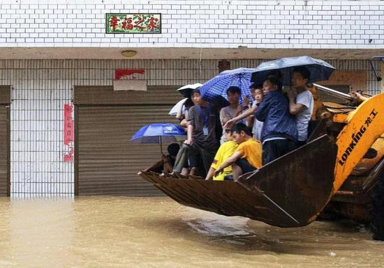 安徽歙县，高考考生们在救援队挖掘车的铲斗里向考场进发