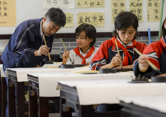  在新疆疏附县托克扎克镇中心小学书法教室内，王庄铁老师在教同学们写毛笔字（2017年9月26日摄）。新华社记者 赵戈 摄