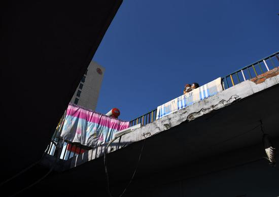 一名患儿和家长在“中途宿舍“房顶的活动区晒太阳。