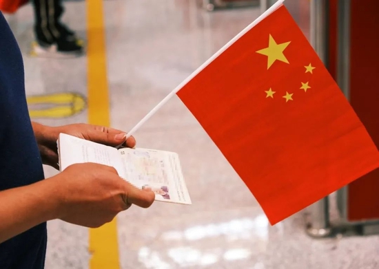 4月29日，在北京首都国际机场，一位拿着国旗和护照的公民等待入境。新华社发（王春晖 摄）