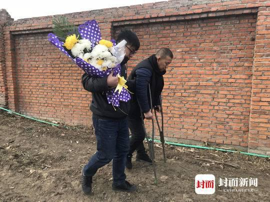 金哲宏在儿子的搀扶下，拄着双拐去祭拜父亲。