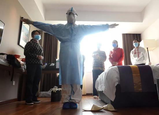 1月29日，一名来自北京安贞医院的医护人员在医疗队驻地向队友演示防护服的穿脱。（新华社图）