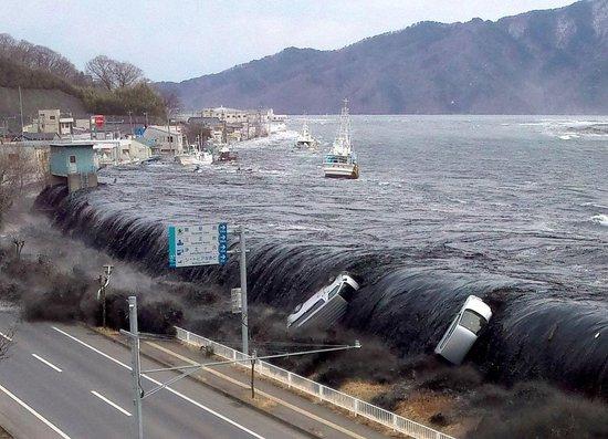  △2011年3月11日拍摄的照片显示，日本东北部海域发生9.0级地震后不久，海啸冲破堤坝并涌入岩手县宫古市。