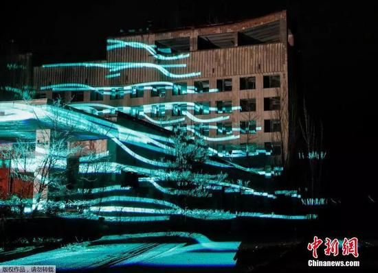  当地时间2018年11月22日，乌克兰普里皮亚季，参观者们在切尔诺贝利核电站附近观看一场“人工”数字雕塑的展示。