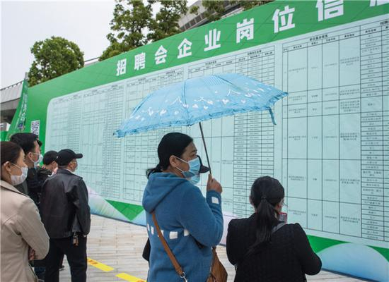 4月21日，求职者在武汉市复工复产企业用工现场招聘会上查看招聘信息。新华社记者 肖艺九 摄