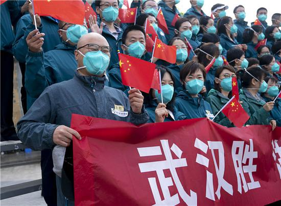  4月15日，北京协和医院国家援鄂抗疫医疗队队员挥舞国旗。当日，北京协和医院国家援鄂抗疫医疗队约180人启程回京。新华社记者 熊琦 摄