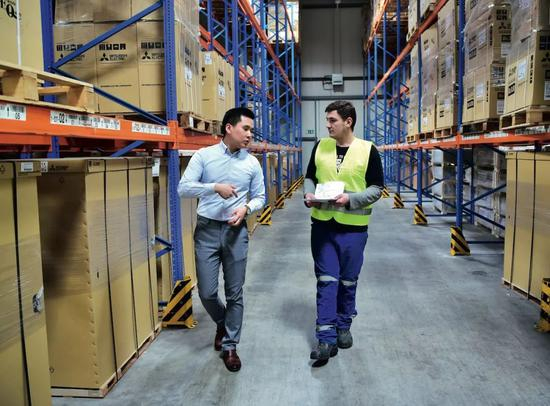  4月16日，在德国杜伊斯堡渝新欧（重庆）物流有限公司的物流仓库，公司商务主管甘宇辰（左）同一名外籍雇员进行业务沟通。近年来，随着中国与欧洲国家共同落实“一带一路”倡议，坐落于德国鲁尔区莱茵河畔的杜伊斯堡，正逐步打造成为德国的“中国城”。2019年初，每周约有35至40列火车往返于德国杜伊斯堡港和中国的十多个城市之间，中欧班列成为杜伊斯堡的一张新名片。越来越多的中国企业来到杜伊斯堡，为“一带一路”中欧班列的建设贡献力量。图/新华