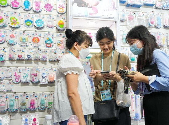  印尼采购商朱丽娅·哈桑（左）和女儿斯太芬妮·杰斯提娜（中）在第133届广交会孕婴童展区与参展商洽谈（4月23日摄）。新华社记者 刘大伟 摄