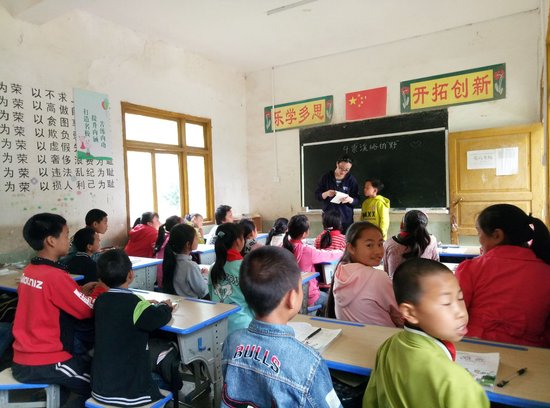 图中穿粉色外套、回头的小女孩是龙海芬 讲台上的老师是曹媛媛