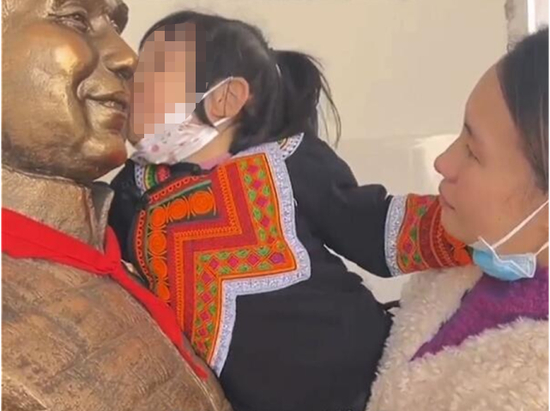 　3岁小女孩亲吻父亲张晓林的雕像。