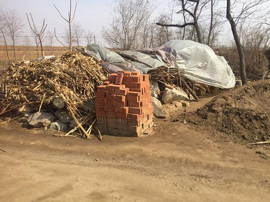 嫌疑人把草垛堆在门口水沟旁。