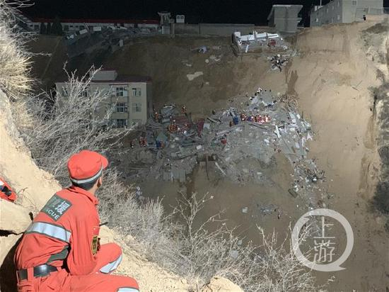  从另一土坡远眺滑坡现场，大量救援人员仍在废墟上搜救。摄影/上游新闻见习记者 贾晨