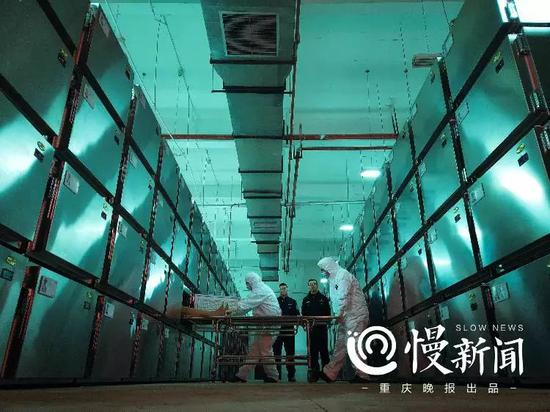 ▲巩强（左）和王小伟（右）把待检尸体拉出来，接下来他们会走向解剖室，揭开一个死亡的真相