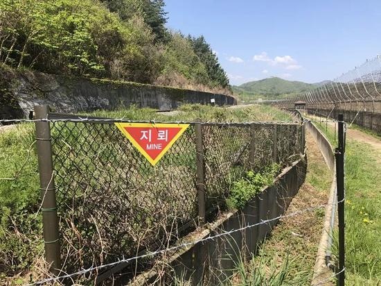  铁丝网上悬挂着的“地雷”警示牌。新华社记者陆睿摄