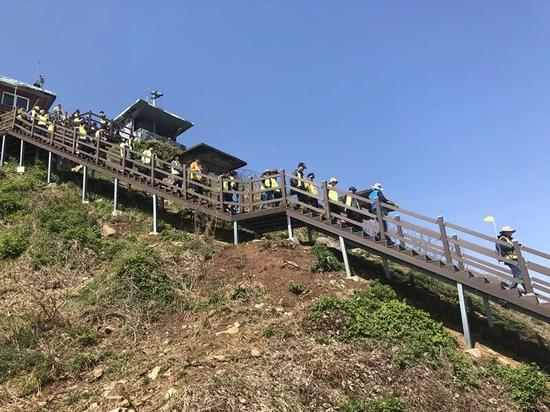  身着青绿色背心的游客在导游带领下进入“非军事区和平之路”步道。新华社记者陆睿摄