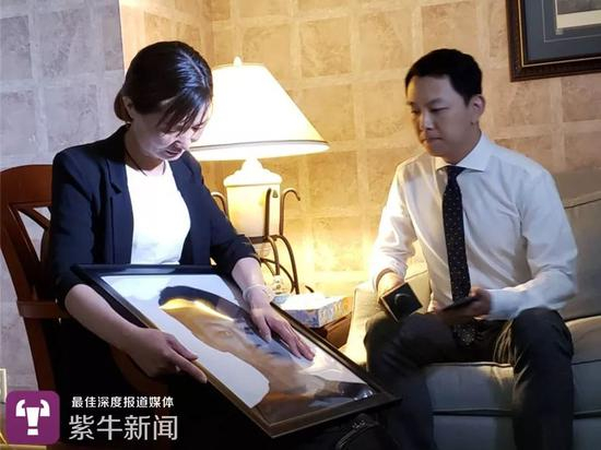 颜洋的妈妈抚摸着儿子的照片接受媒体采访
