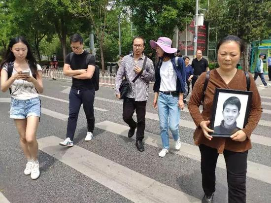 ▷&nbsp;谢雕父母在法院前捧着儿子的遗像