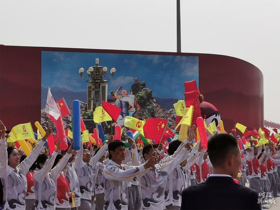 △“众志成城”方阵经过时，大屏幕上打出了“敬礼娃娃”当年的照片。