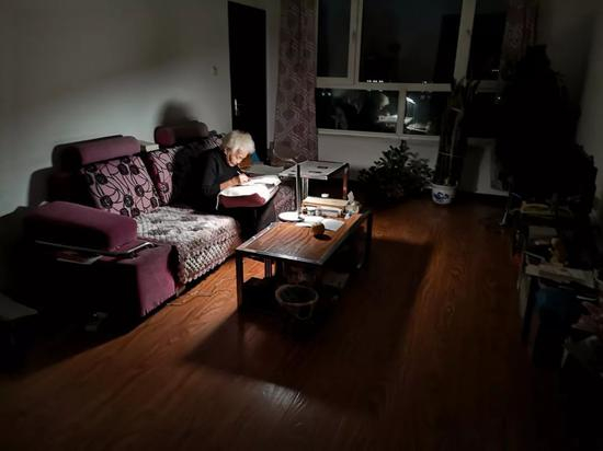 在黑龙江省绥化市北林区，姜淑梅老人在家中将沙发靠垫垫在腿上写作（9月24日摄）。新华社记者 杨思琪 摄